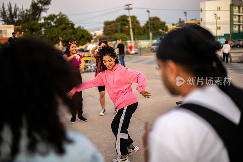 年轻女子在街头派对上与她的朋友跳霹雳舞