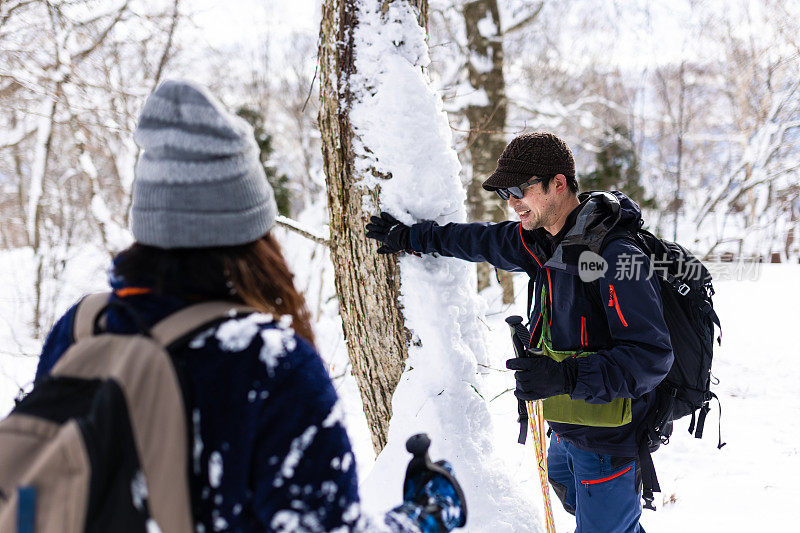 两个穿着雪鞋的人在冬天的森林里停下来休息