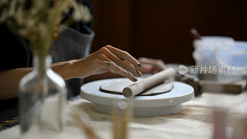 一名男艺术家在陶瓷轮上用泥辊揉生粘土的特写图像
