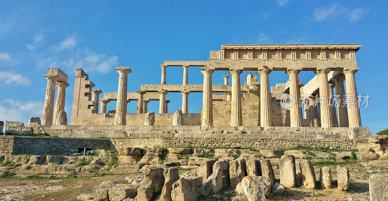 希腊埃吉纳岛上的阿法亚神庙遗址(爱琴海萨罗尼克群岛)上有古罗马石柱，天空蔚蓝金色小时柔光(女神纪念碑)历史遗迹，希腊地中海