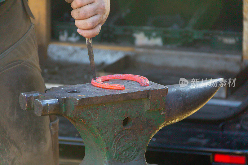 铁砧上炙热的红色金属马蹄铁的特写镜头，铁蹄铁匠在铁砧上工作，使其形状适合马的脚。