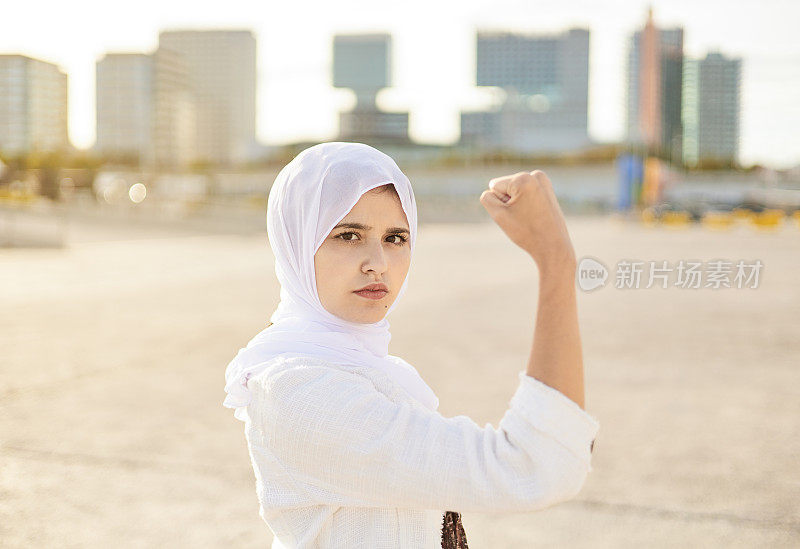 一幅穆斯林妇女弯曲肱二头肌的肖像。女性权力和女权主义的概念。