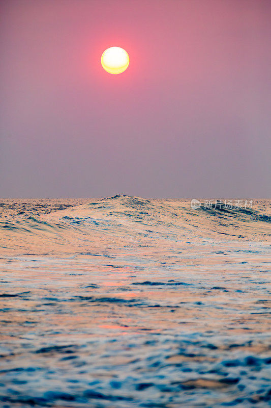 日落在海浪:一个宁静的场景与粉红色和紫色的天空颜色。