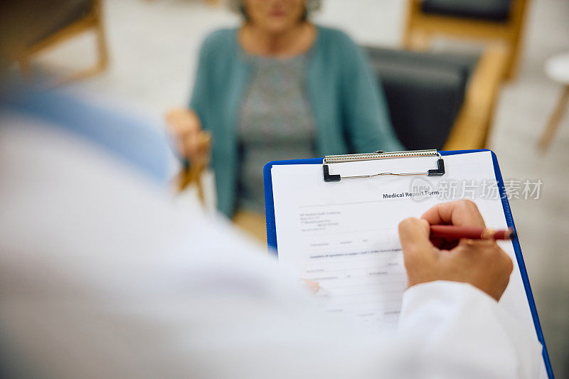 女医生与病人预约时在医疗报告中书写数据的近景。