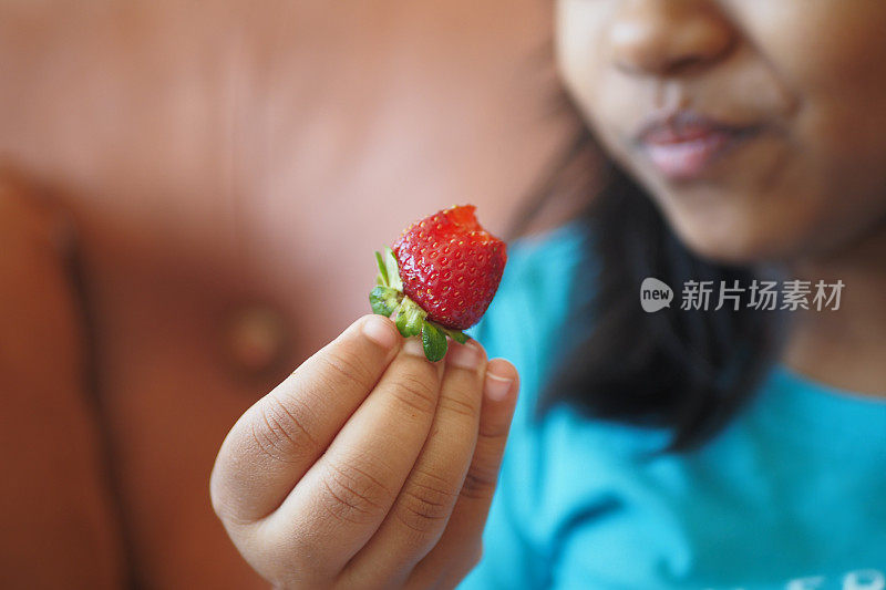 孩子坐在沙发上吃草莓