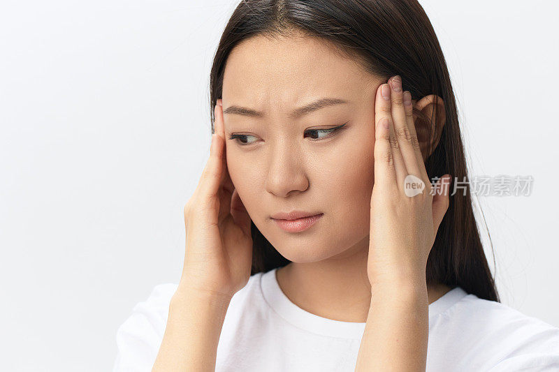 偏头痛。痛苦的头痛的侧面视图，晒黑的美丽年轻的亚洲女人抚摸额头，在白色的背景上摆出孤立的姿势。伤害，不良健康，疾病概念。酷炫报价横幅