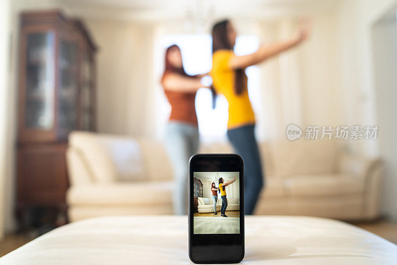 两个女人一边跳舞一边用智能手机录音