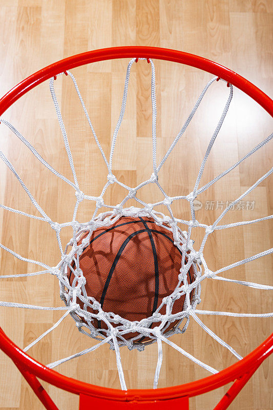 看着篮球穿过球网，背景是球场的木地板