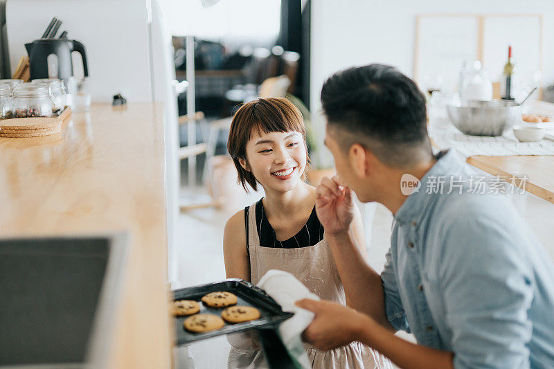 快乐的年轻亚洲夫妇品尝新鲜的家庭厨房烤制的饼干