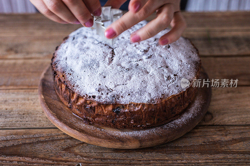 厨师用巧克力屑和松树形状的模具装饰新鲜制作的圣诞饼干