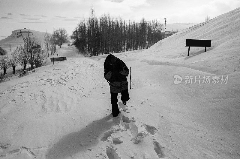 穿着暖和的衣服在雪地上行走的女人