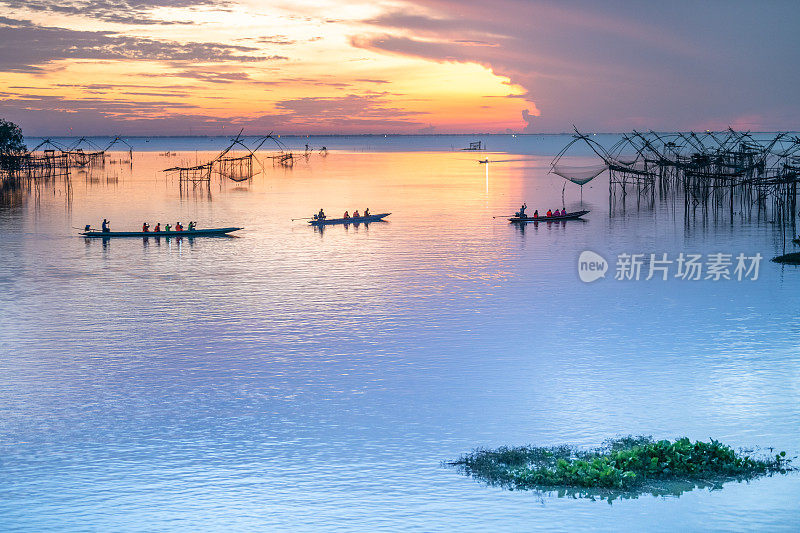 日出时分的渔村用剪影的木制渔网、渔网和泰国的长尾木船