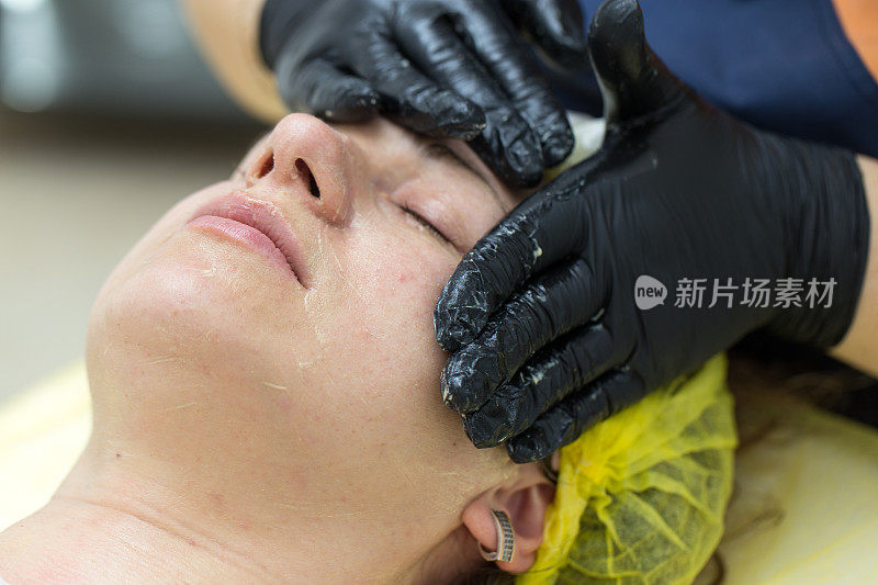美容师用手按摩女性脸上的皮肤。
