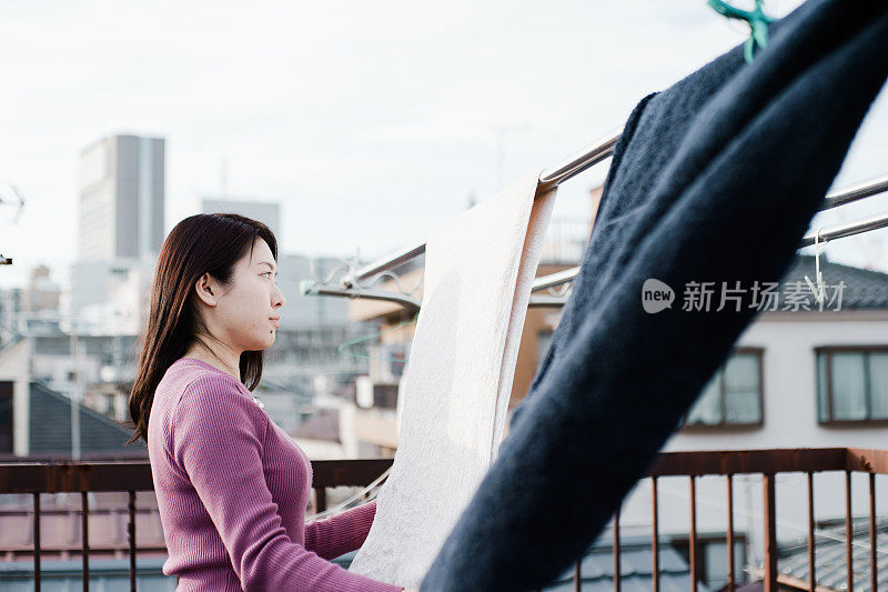 一个亚洲女人在屋顶上晾衣服的照片