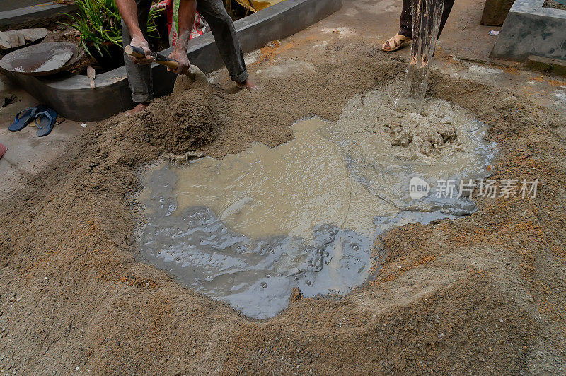 印度劳工用铲子搅拌水泥。