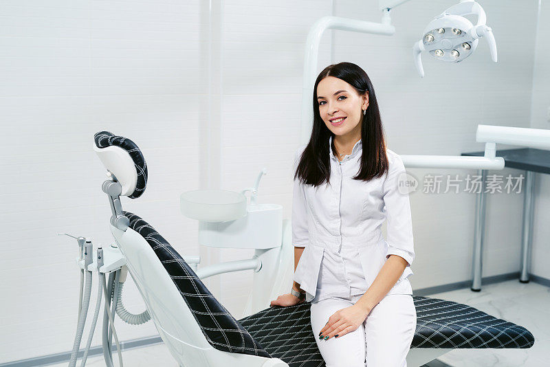 一个微笑的女牙医在现代牙科诊所的办公室的肖像。