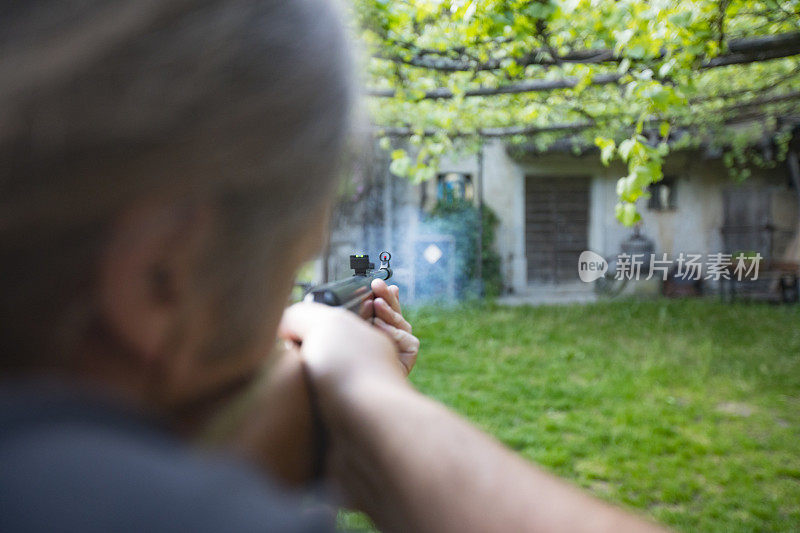 一名成年男子在前院用气枪射击目标