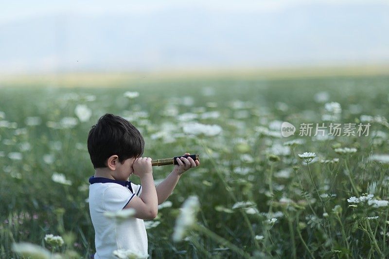 小男孩年轻的研究员抬起头，用双筒望远镜探索着