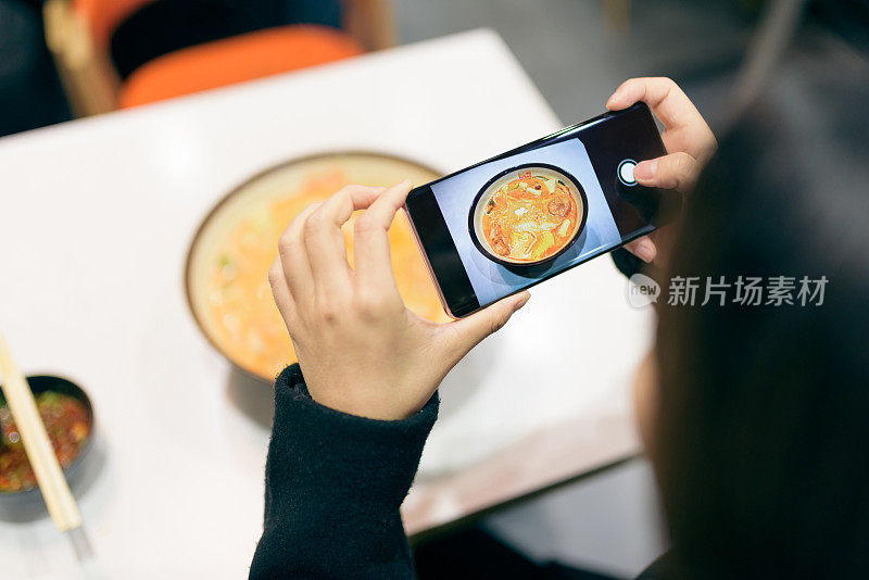 年轻女子用智能手机拍食物。