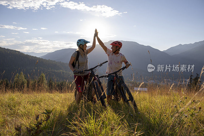 山地电动自行车夫妇在高山草甸击掌