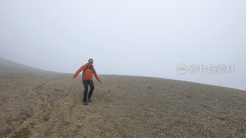 年轻的女登山运动员在雾中爬下一座山