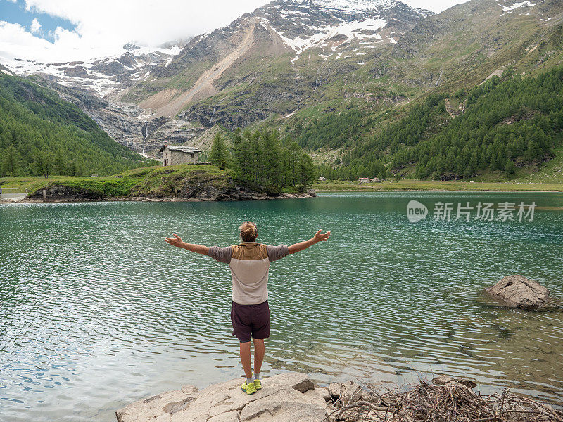 一个人在高山湖边放松，胳膊伸着