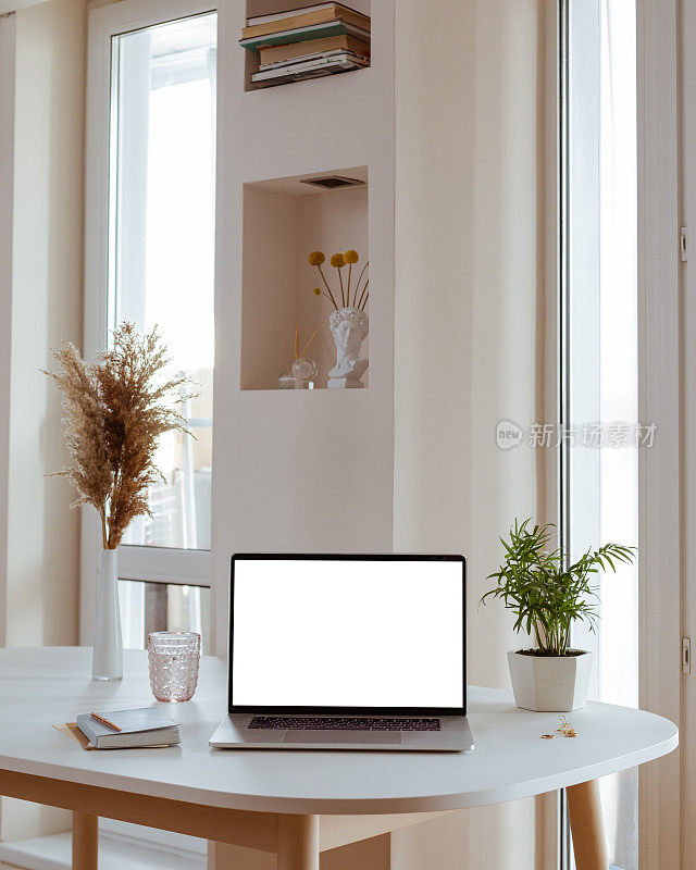 笔记本电脑与空白白色屏幕在办公室办公桌内部。时尚的工作模型。