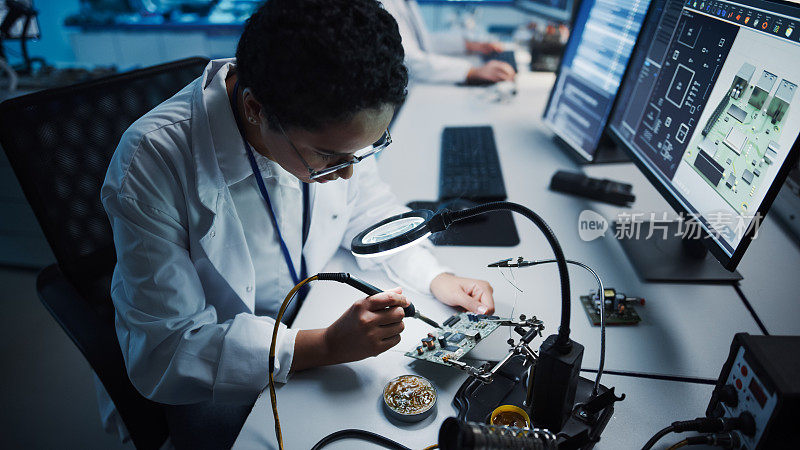 现代电子研究，发展设施:黑人女工程师做电脑主板焊接。科学家设计工业PCB，硅微芯片，半导体。俯拍