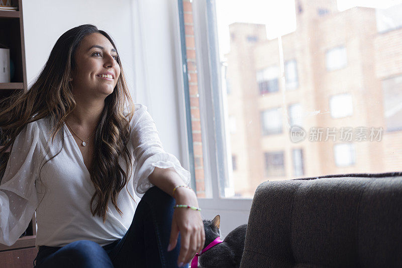 美丽的年轻女子透过她的窗户看着邻居，而她很高兴看到一些吸引她的注意