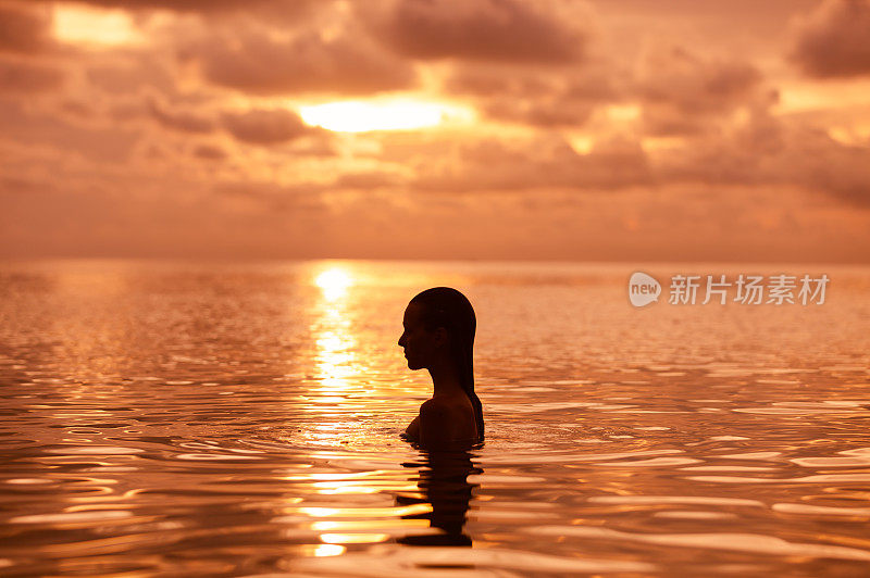 日落时分在水里放松的女人。