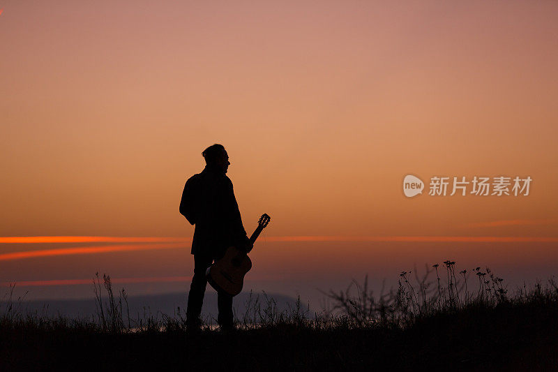 夕阳中拿着吉他的男人