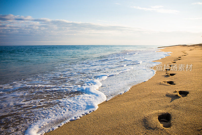 日落时沙滩上的脚印的特写