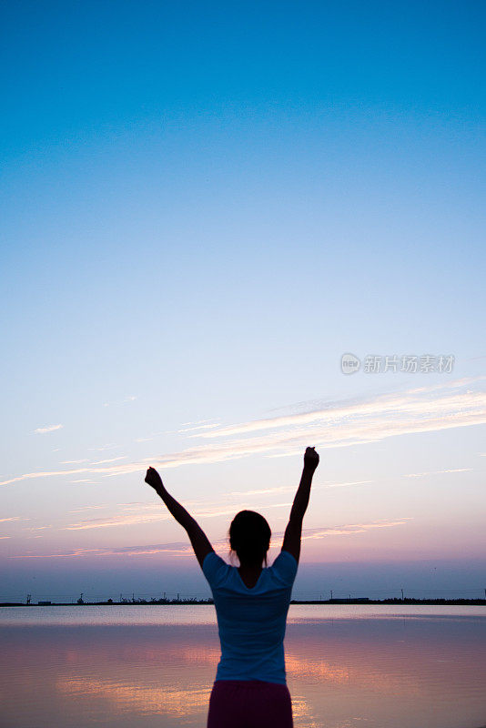 年轻女子在湖边举起双臂