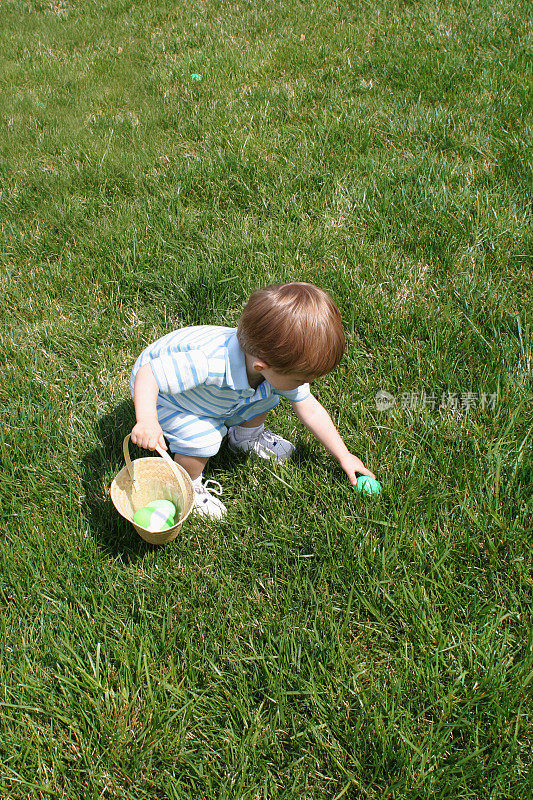 小男孩在草地上发现了复活节彩蛋