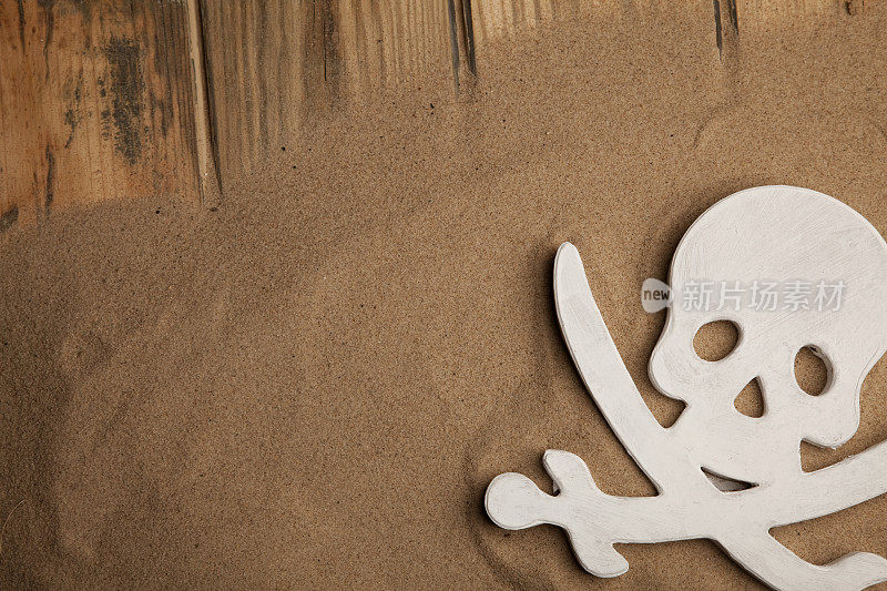 骷髅和交叉的骨头在沙子的背景上