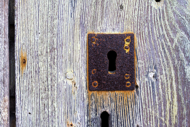 锈迹斑斑的古董锁孔在风化木门上，意大利