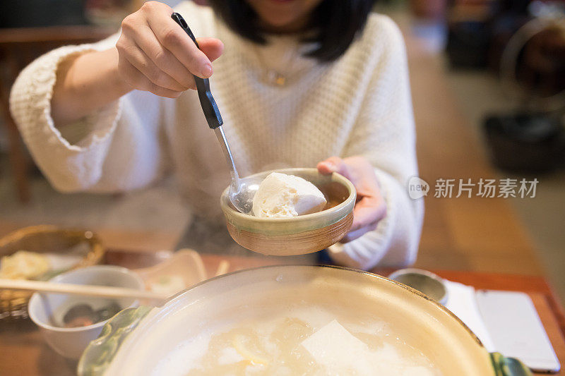 年轻女子从火锅里捡豆腐