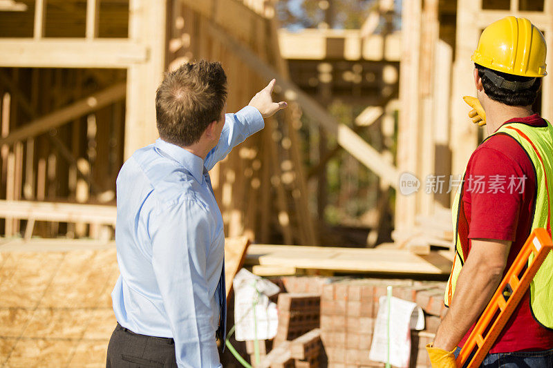 建筑工人，房地产开发商在工地讨论工作。