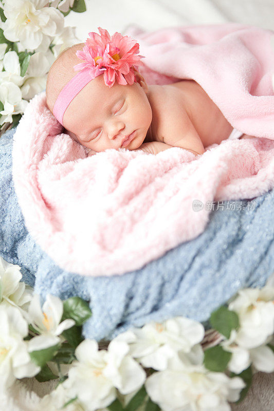 熟睡的新生婴儿戴着粉色和蓝色的头巾