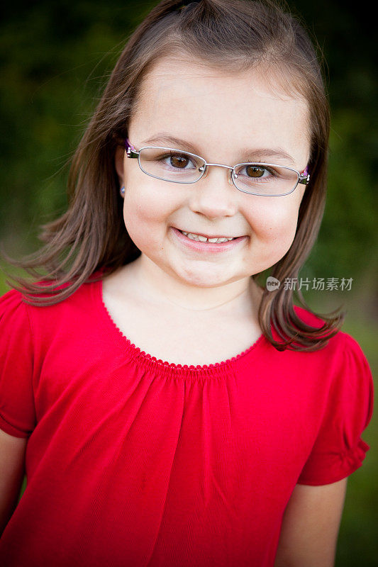 戴眼镜的快乐年轻女孩在外面微笑