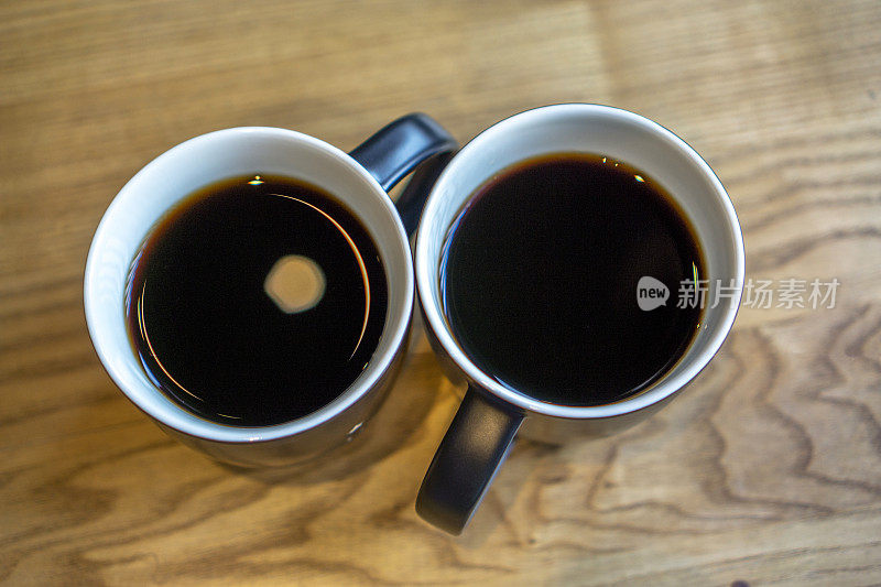 木桌上放着两杯黑咖啡