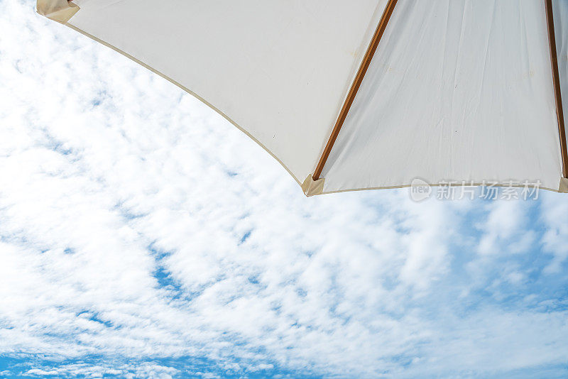 沙滩伞和多云的蓝天背景