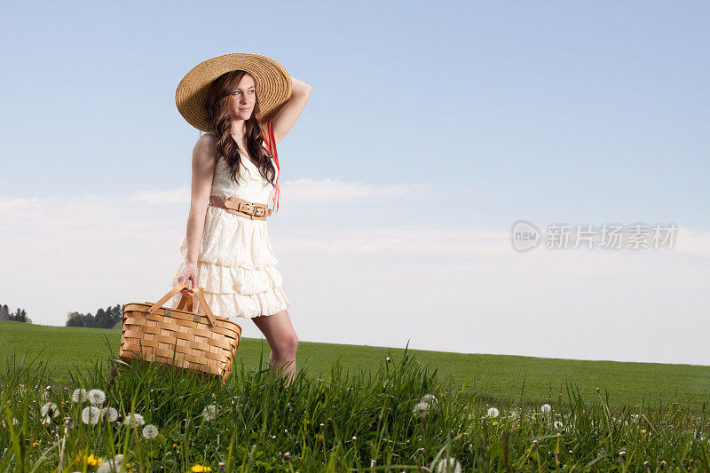 带着野餐篮的年轻女子在草地上