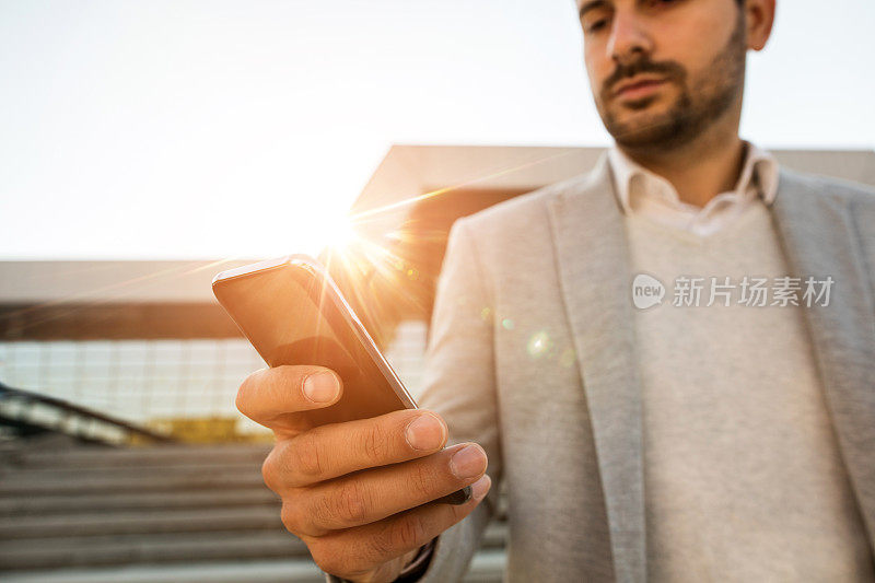 近距离的商人输入信息的手机在户外。