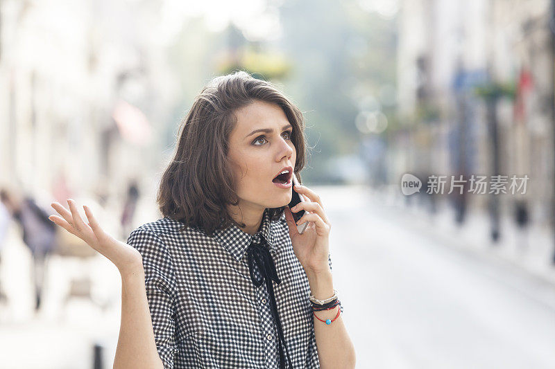 年轻女子在街上用智能手机打电话