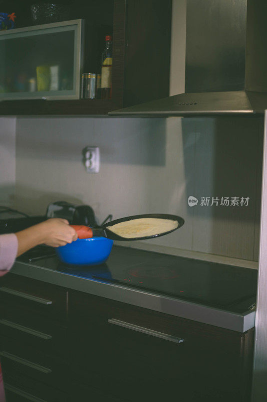 女孩倒了一勺面团做煎饼。在家做煎饼。