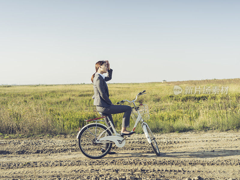 一个年轻的女商人坐在乡下的bicyale上的肖像