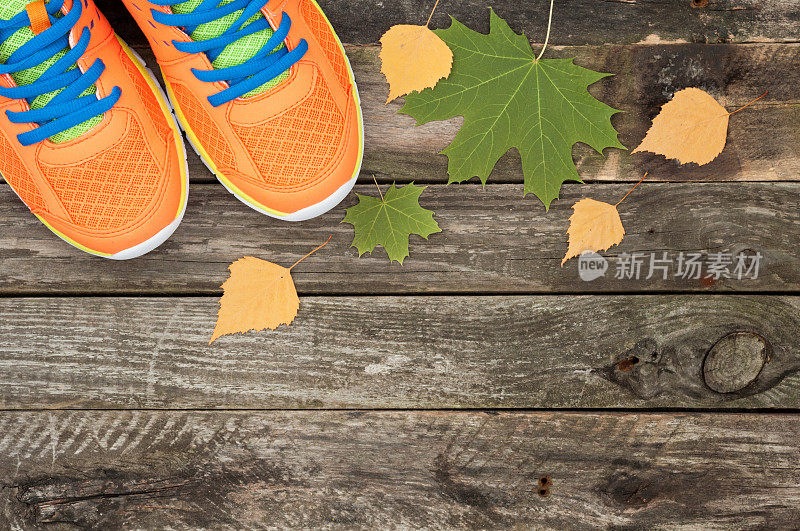 运动鞋和秋叶在白色的木制背景。俯视图运动设备。秋季户外运动。俯视图