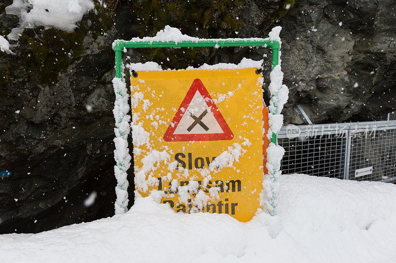 滑雪道上被雪覆盖的减速标志