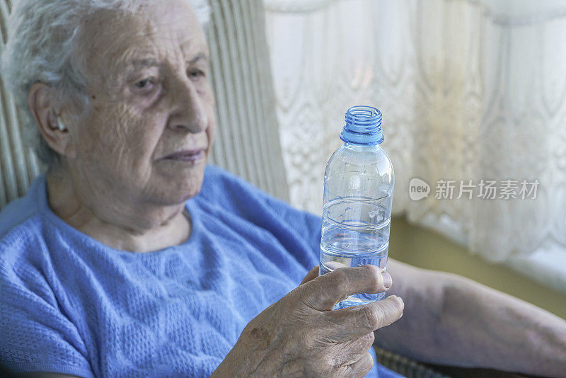 老妇人拿着一瓶饮用水